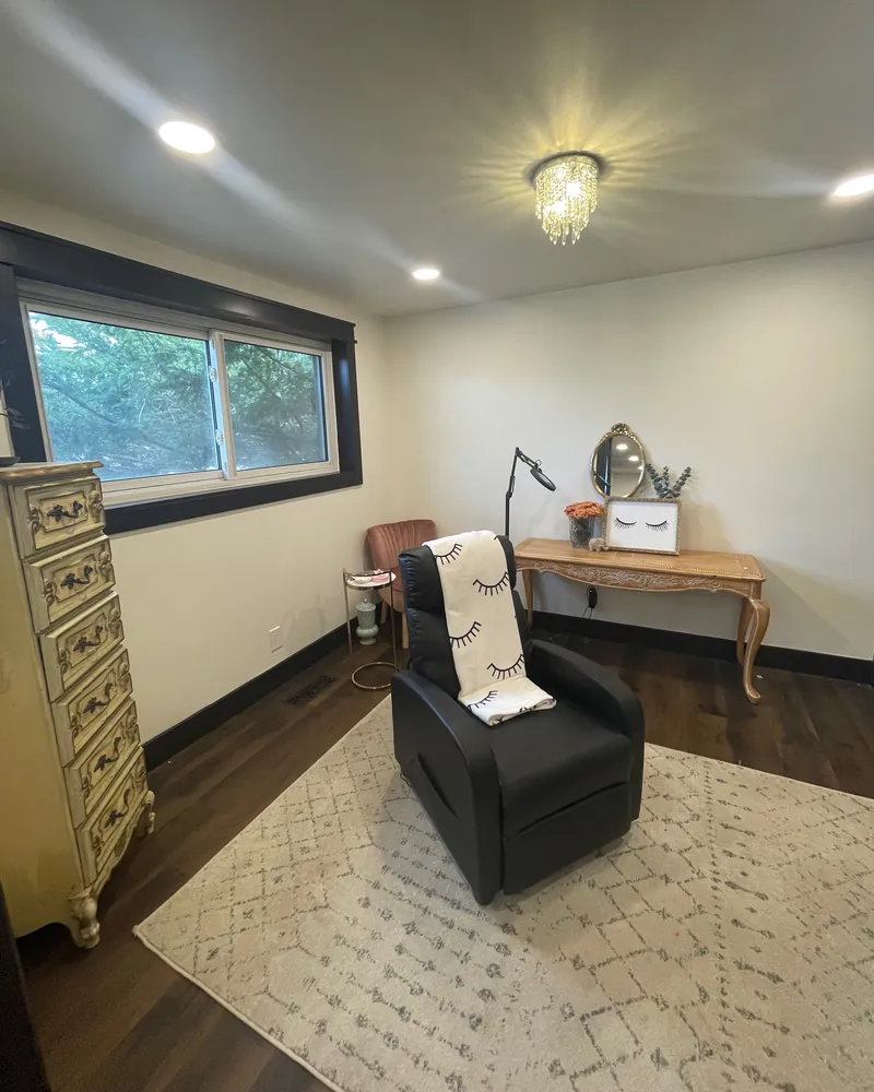 The Sage & Lash treatment room: a black lash recliner with an eyelash-print throw, a vanity and a window