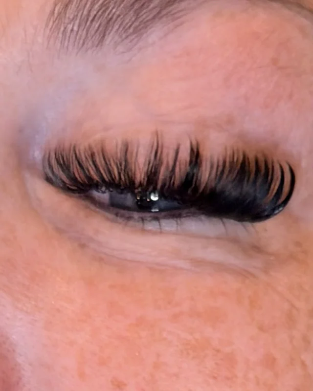 Close-up of a full, dark volume lash set on a closed eye